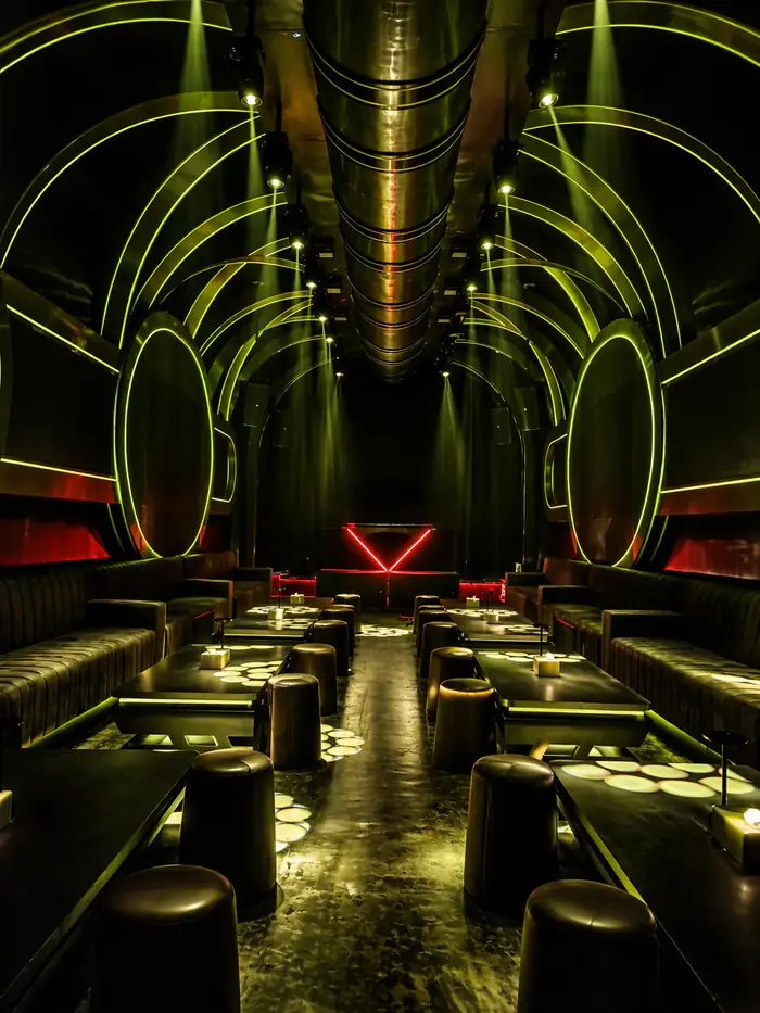 Lounge V-KTV PIK 2 — kursi banquette, pencahayaan hijau ambient, dan papan neon V