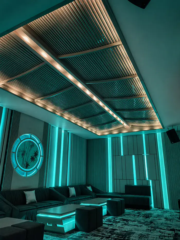 Ruang karaoke privat V-KTV PIK 2 dengan pencahayaan cyan dan panel kayu langit-langit